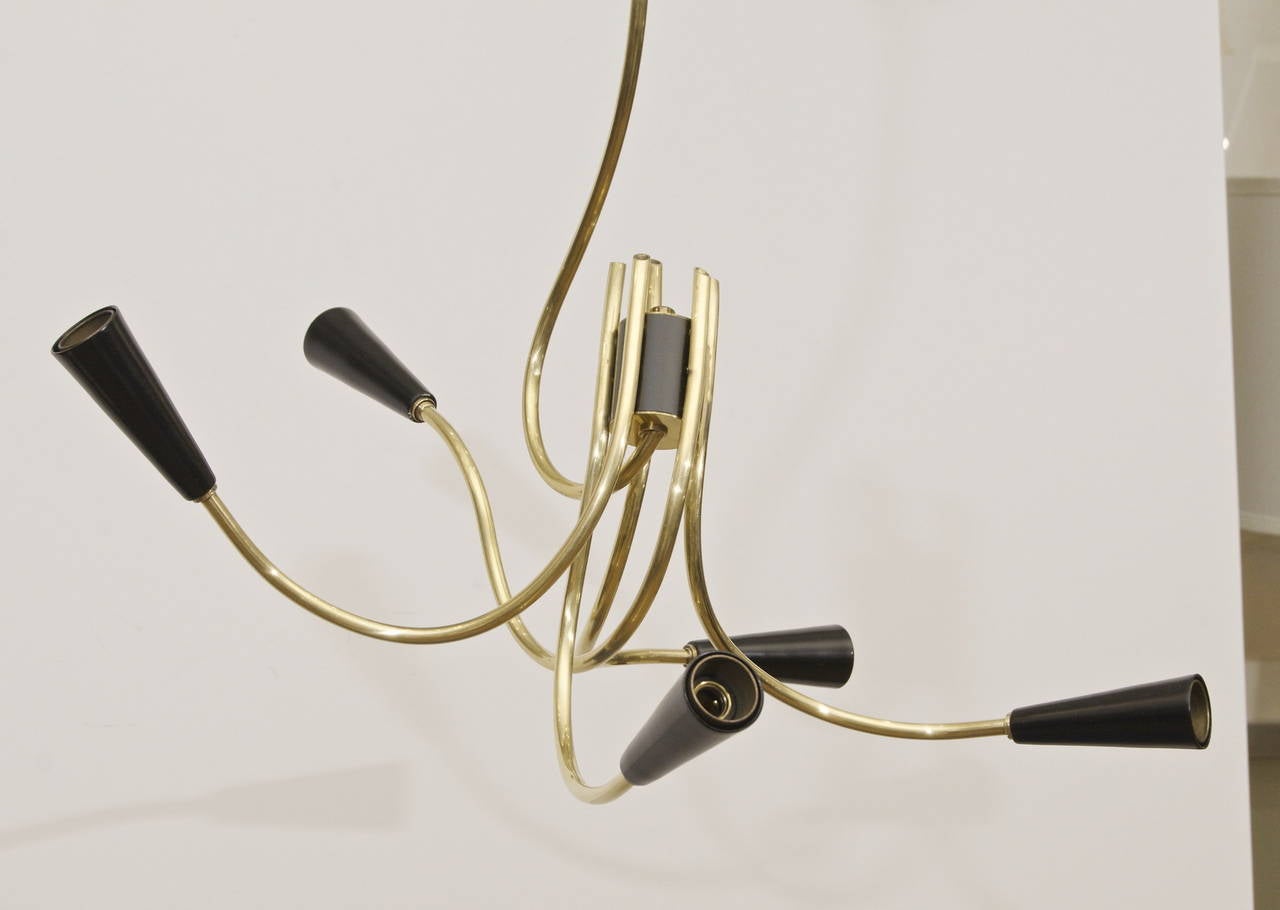 An extremely unusual and highly asymmetrical Stilnovo style chandelier, the five brass arms sinuously interlacing and curving in abstract fashion to satin black enameled socket caps.

Takes five E-14 base bulbs up to 40 watts per bulb, new