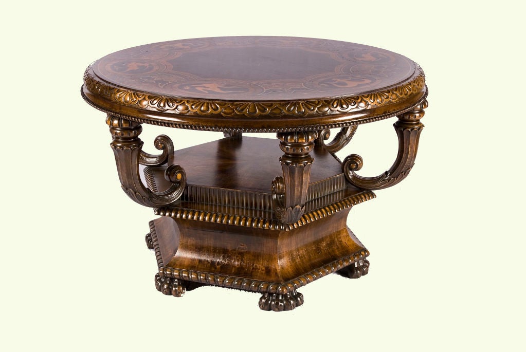 The stunning inlaid marquetry designs on the the table top serve as the perfect complement to the scrolled supports below.  The multi-footed hexagonal base has an architectural feel and contrasts whimsically with the circular top.