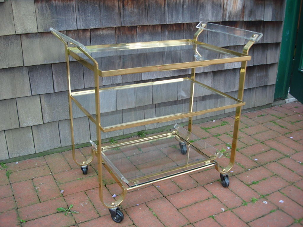 Super high-quality flatbar brass bar cart on casters with lucite handles. Bottom shelf functions as a serving tray. Made by legendary metal shop, Treitel Gratz, known for handling metal fabrication for such design icons as Donald Deskey, Raymond