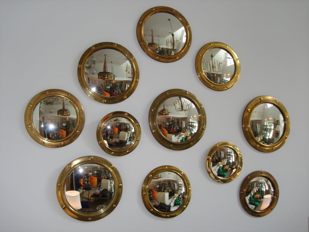 WOW, what a statement - this grouping of vintage English convex porthole mirrors with brass frames.  As shown, the patina on these mirrors vary and work beautifully as an art installation.