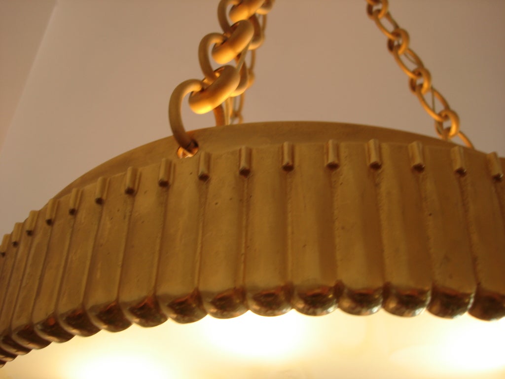 An Art Deco style hanging plafonnier with frosted glass and satin dore finish. Thick chain link and canopy finish off this very heavy light fixture. Six-light candle style to interior.