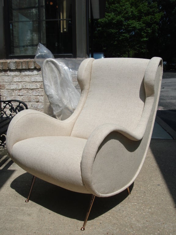 Rare outline form on these sculptural armchairs with polished brass tapering legs.