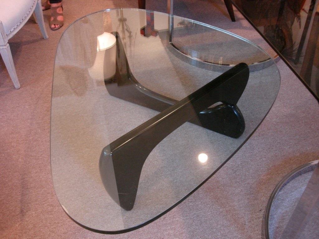 Early low table (IN-50) with an asymmetrical glass atop interconnecing wood base supports.