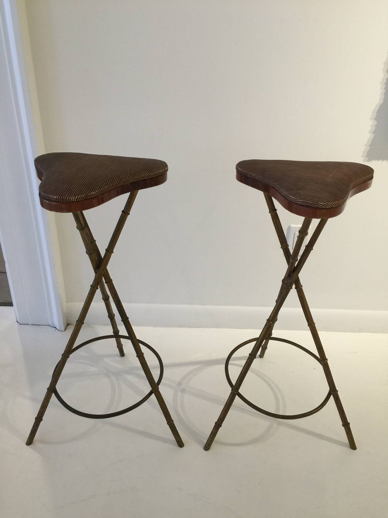 Designed by Jacques Adnet, this pair of gilt metal bamboo style bar stools are all original with vinyl upholstery and wood banding to seat. All original.