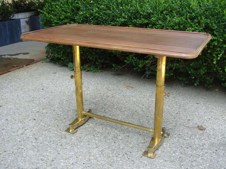 Salvaged French yacht table with lateral panels that can be raised for additional surface area and brass legs that have been polished to return some of this tables original beauty.  Stands solidly and perfectly as shown.  Can be raised lower to be