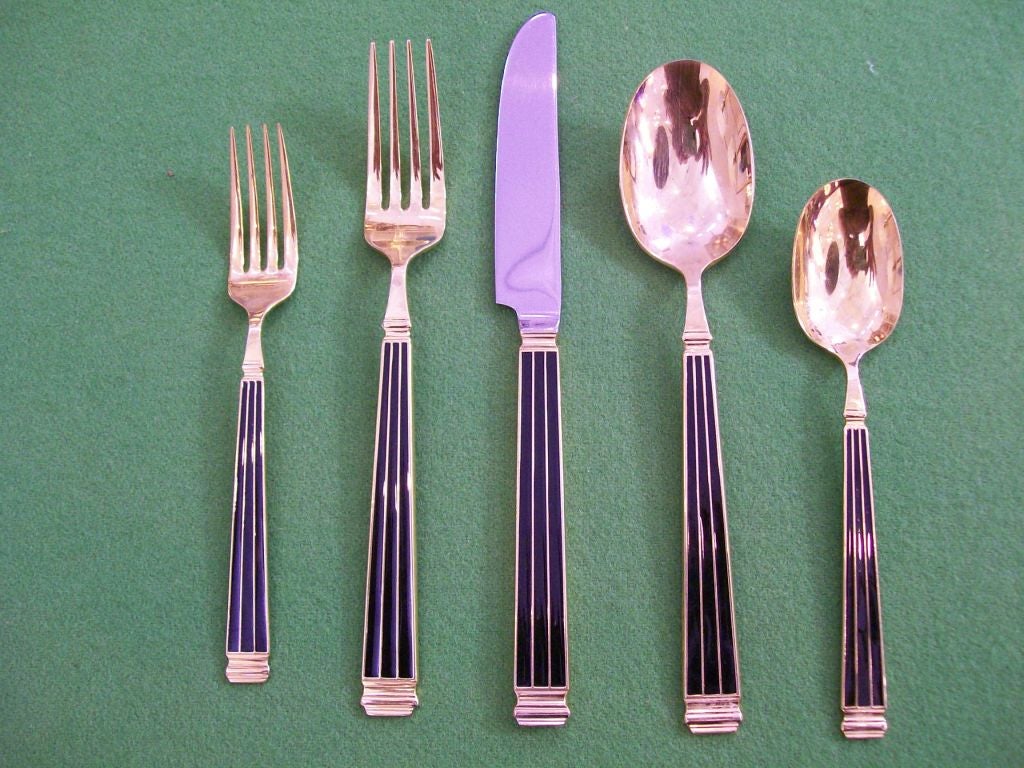 Made in Japan - 24k gold on black enamel and green enamel pieces.   Six 5-piece place settings in mixed green (4) and black (2).  Additional pieces include black knives (2) and soup spoons (2),salad fork, dinner fork and green salad fork, dinner