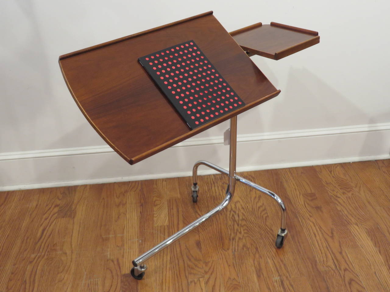 Two way adjustable, wood and chrome Danish reading or writing table on wheels. Larger work area tilts to required angle for reading or writing, while the smaller surface is level and can be used for food or drinks. Overall height can be raised to