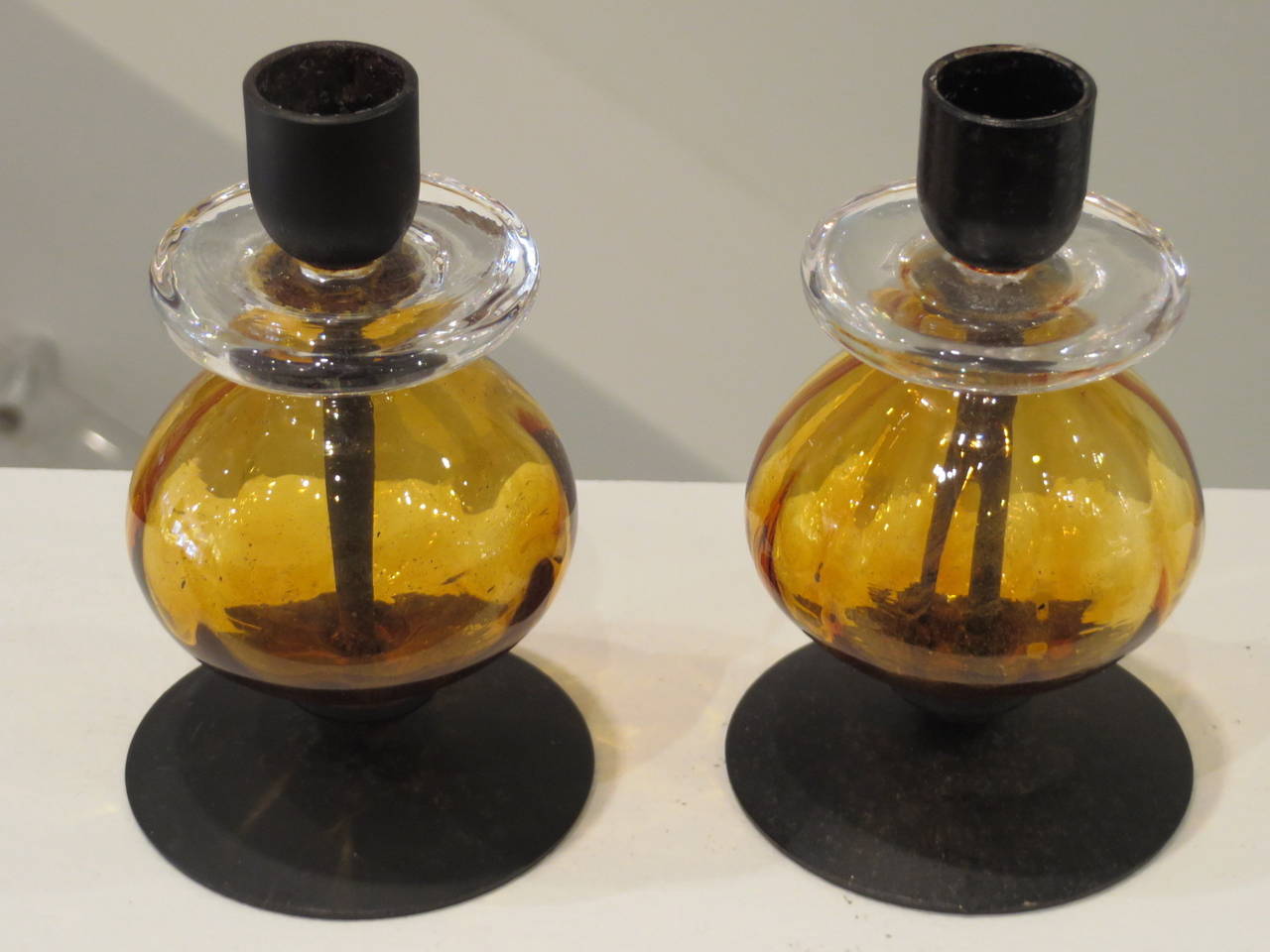Lovely pair of amber, with clear glass and wrought iron candlesticks by Erik Hoglund for Kosta Boda.