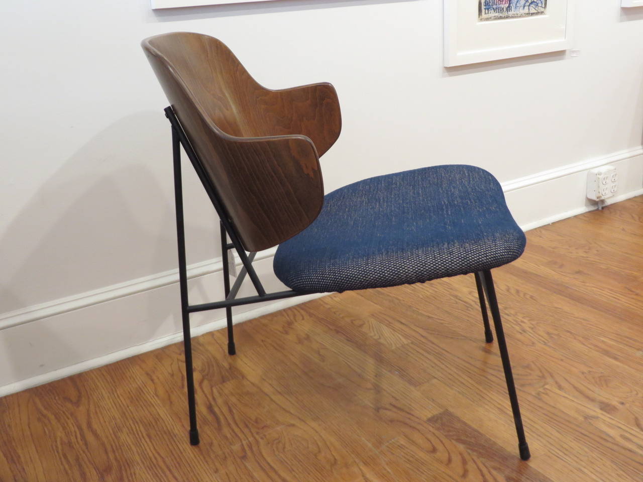 1950s armchair by Danish designer Ib Kofod-Larsen. He designed variations of this easy chair in metal and wood and all retain the iconic large back and joinery of the legs to the backrest. The chair is very comfortable and looks great from every