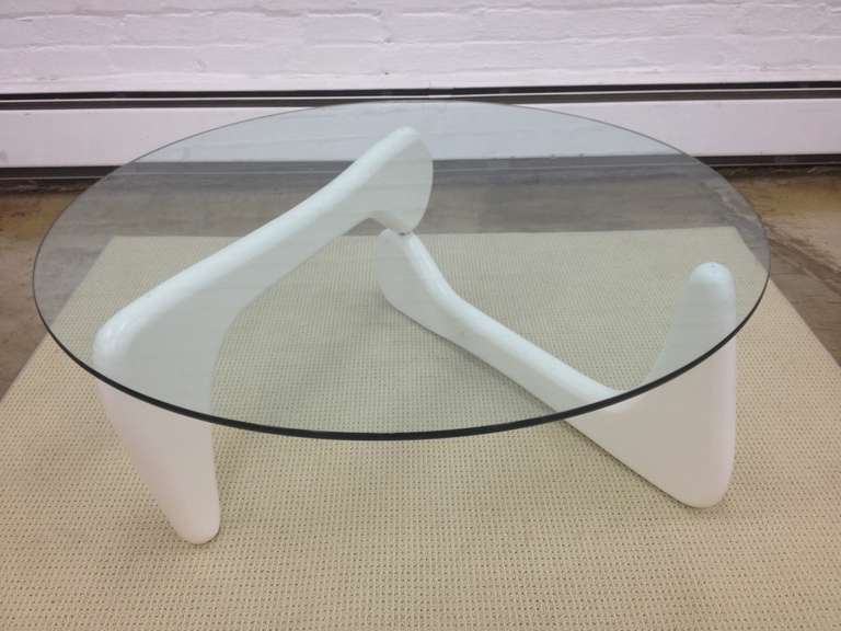 Isamu Noguchi coffee table recently transformed in white lacquer.  Iconic Noguchi form looks appealing in white with round glass.  The base is interconnected on pivoting supports.