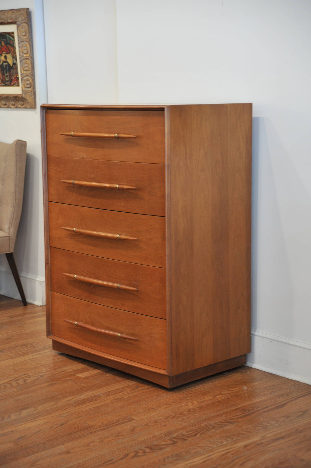 Tall five-drawer dresser designed by T.H. Robsjohn-Gibbings for Widdicomb. The wood has a warm tone. The drawers have unusual sleek pulls with brass detail. These pulls are rarely seen. Abundant storage with top divided drawers.