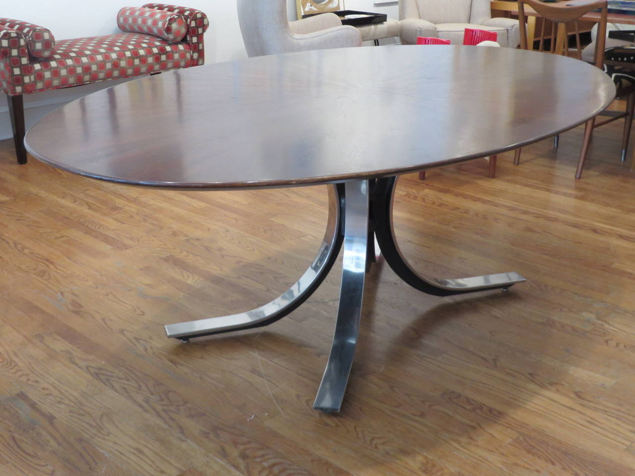 Dining or conference table designed by Osvaldo Borsani for Stow Davis. The tabletop has a bookmatched sunburst pattern with a knife edged bevel. The base is polished steel.