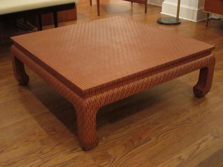 Asian style coffee table, wrapped in a red-cinnabar lacquered linen with an elongated overall pattern.