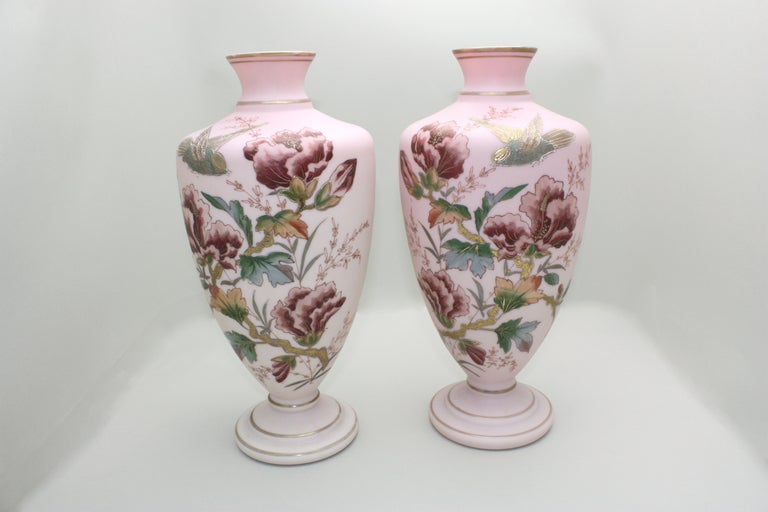 This is a well matched pair of Bohemian or French handblown vases shading from a subtle pale rose to a slightly darker shade as it reaches the top rim. They are decorated with an Aesthetic Movement style in lovely polychrome enamel floral and bird