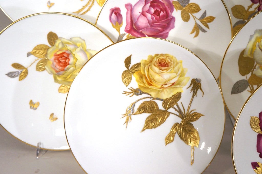 This exquisite set of 12 Mintons cabinet plates or dessert plates feature superbly painted rose specimens, each uniquely painted in a naturalistic palette. Deep magenta, soft pinks and yellow make a rose garden on your table. The leaves and roses