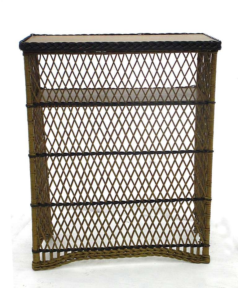 Antique wicker dry bar in original mustard-green painted finish with evenly worn black painted trim.  Wooden top & storage shelf with woven braided borders have a wash of the same mustard-green coloring, showing oak grain.  Hallmark criss-crossing