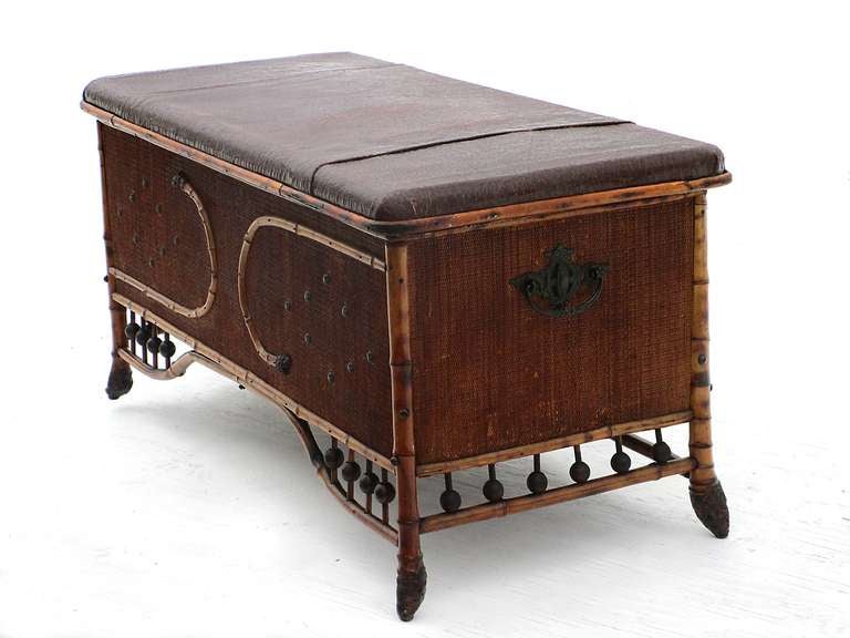 19th century bamboo trunk with all sides covered in woven seagrass and a leather covered lift-top.  Useful height & surface for coffee table.  Decorative bent applied bamboo on front with a diamond shape of applied metal buttons. Fancy metal handles