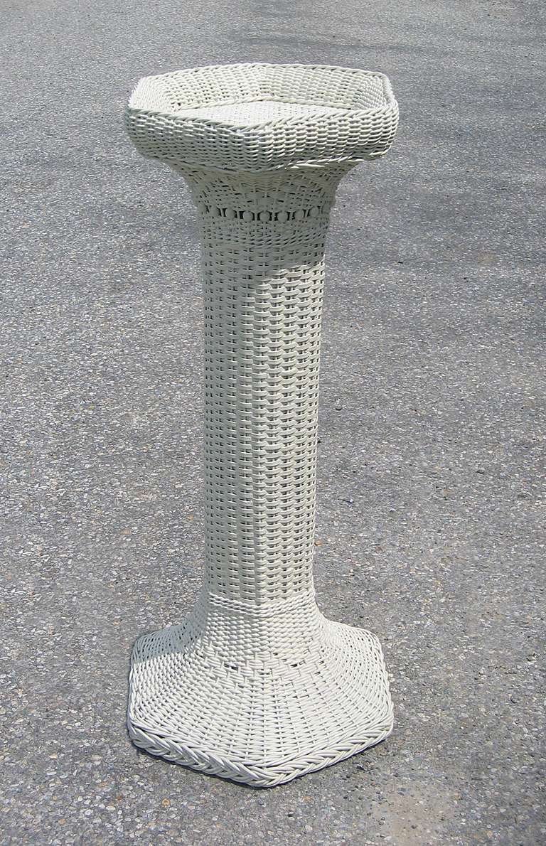 Victorian wicker pedestal in white painted finish. Rolled edge on top with basket-weave flat surface.   Woven zig-zag pattern with row of wooden beads at top of cylinder.  Same pattern is repeated on base and finished with a braided border.  Made of