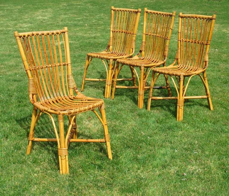 Set of four matching Stick Wicker dining chairs in honey-toned natural stained finish. Squared back frames with traditional paired strands and multiple cane wrappings. Suitable chairs for dining or use at game table.