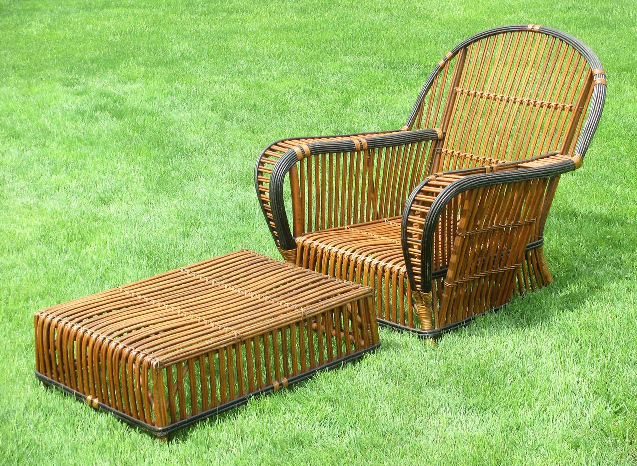 High style Stick Wicker armchair & matching ottoman in honey-toned natural stained finish with black trim. Large scale, deep seated & wide flat arms, the left arm having a woven magazine pocket. Closely paired reeds overall. Large, level ottoman
