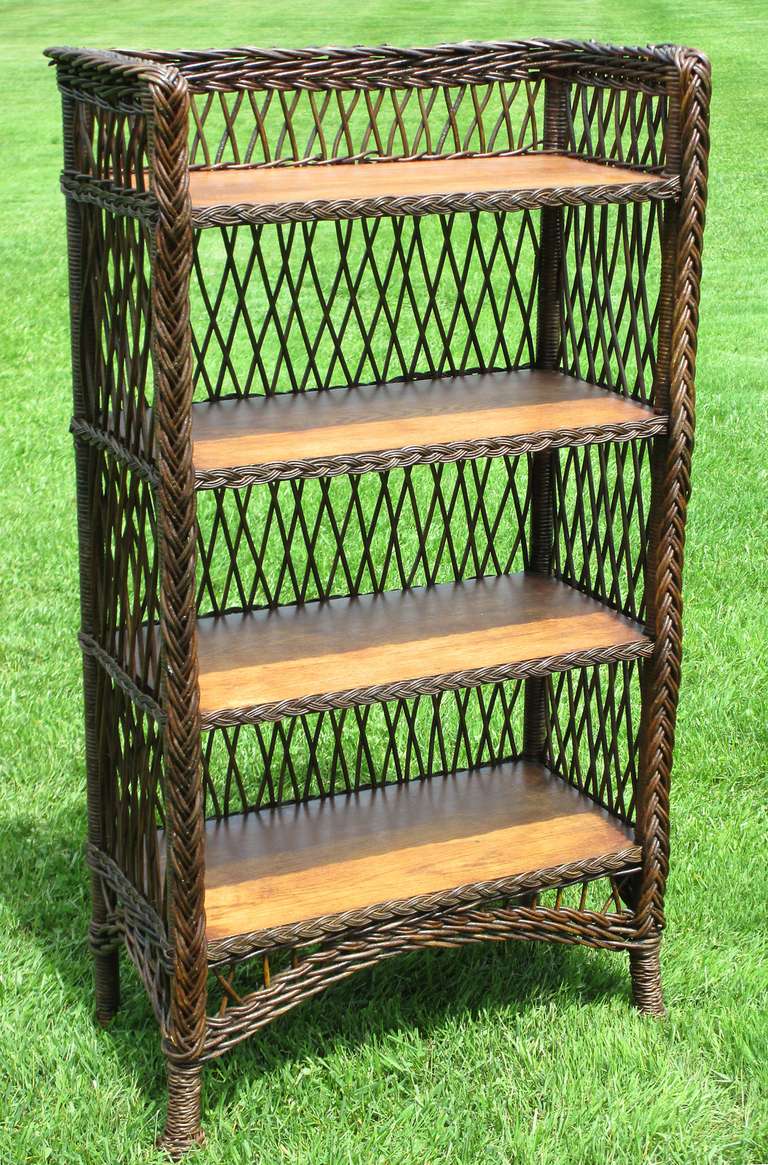 Bar Harbor wicker bookcase in dark natural stained finish. Four solid oak shelves finished with braided border. Three-sided wicker gallery surrounding top shelf. Traditional open criss-crossed lattice design overall. Pine-apple twist-wrapped front