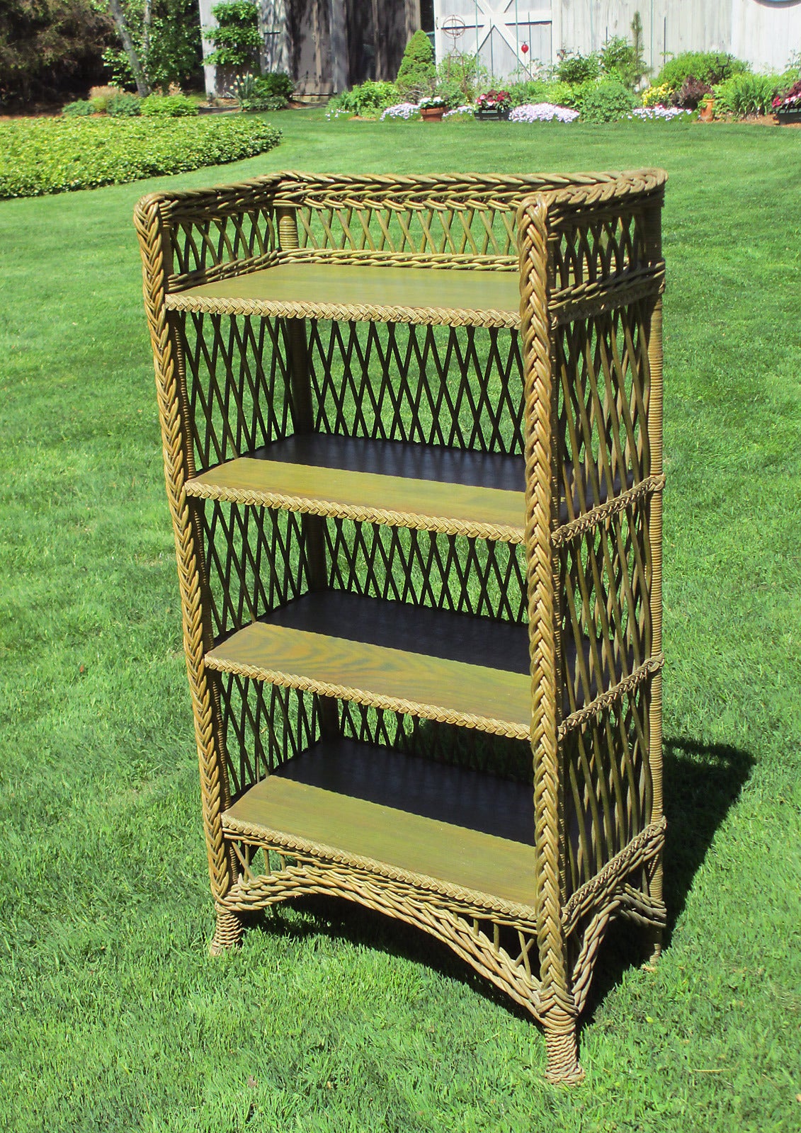 Classic Bar Harbor wicker bookcase in original green stained finish. Four solid oak shelves finished with braided border. Three-sided wicker gallery surrounding top shelf. Traditional open criss-crossed lattice design overall. Pine-apple