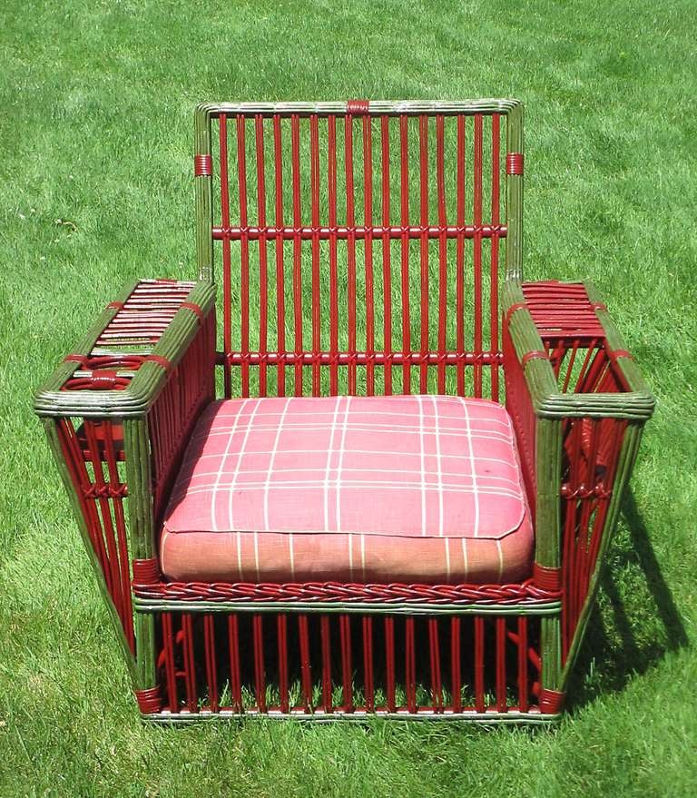 Large scale Stick Wicker armchair in old red painted finish with green glazed trim.  Large magazine holder in left arm, & double beverage holder in left arm.Closely paired reeds overall.  Coiled spring seat platform with new fabric decking under