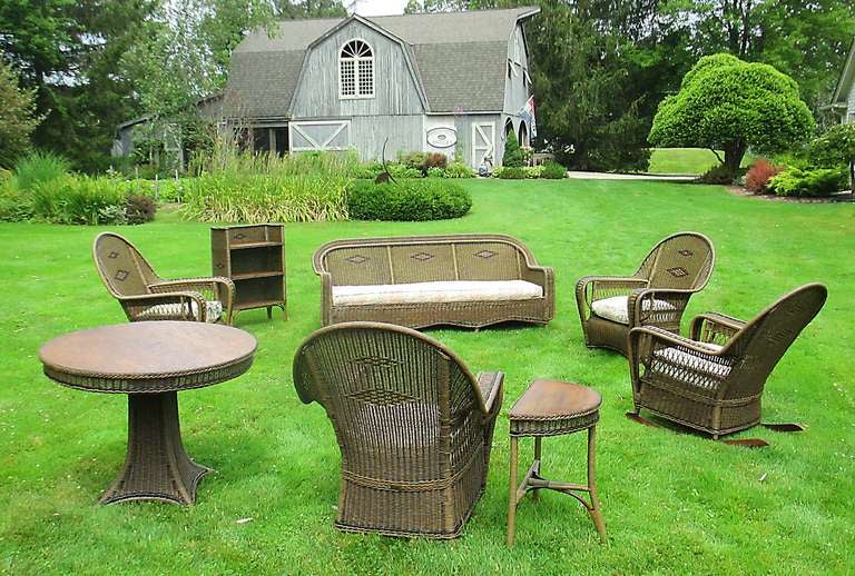 Outstanding 8-Piece Art Deco Wicker Suite in original finish with red & black accents.  Suite consists of sofa 2 armchairs, 2 rocking chairs, round pedestal table, demi-lune table, & bookcase.  Large scale seating in  high style form having halmark