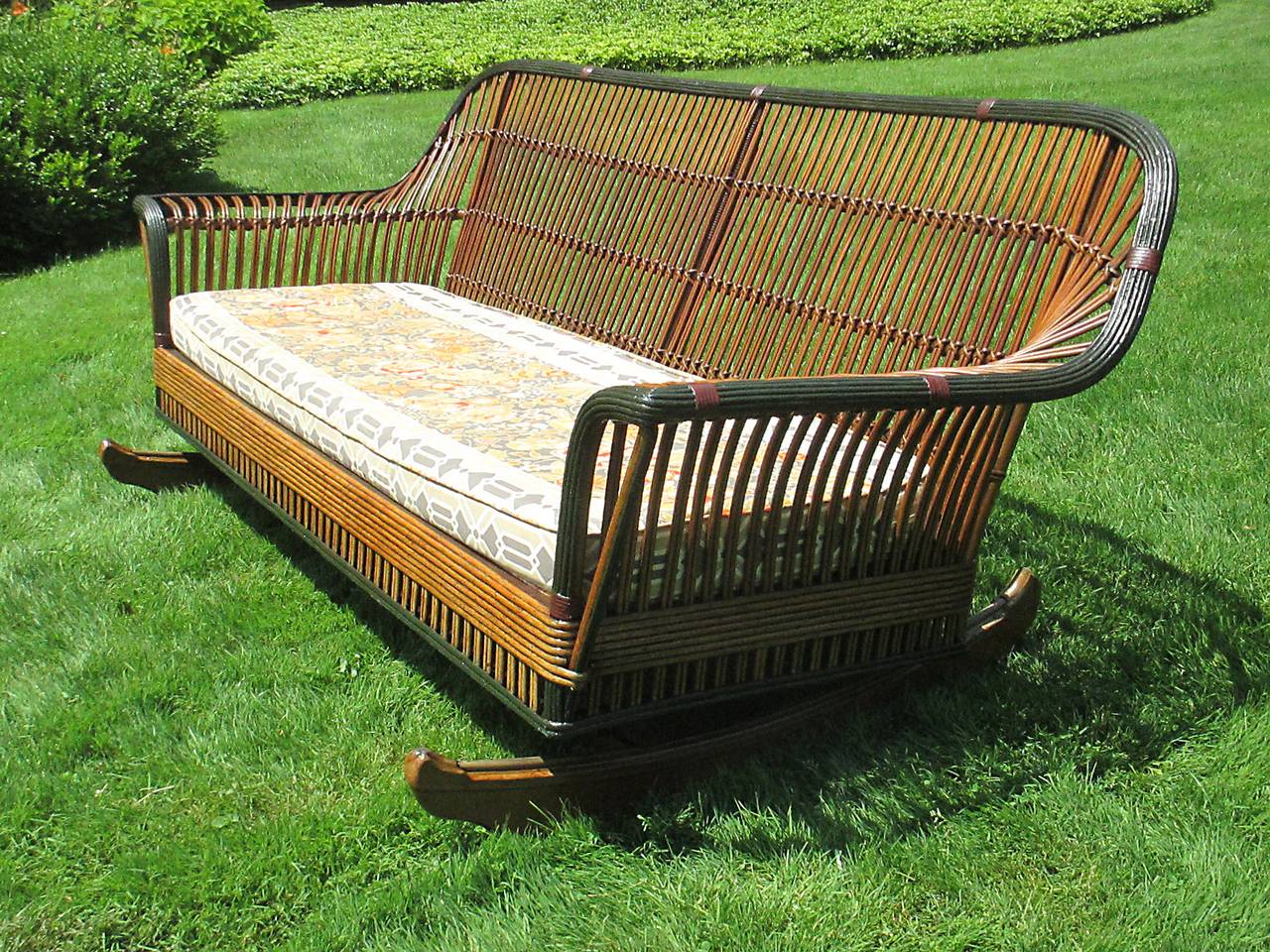 Extremely rare Stick Wicker glider.   Original metal wheels glide the piece back and forth with old fashioned ease on a wooden platform.  The length (83