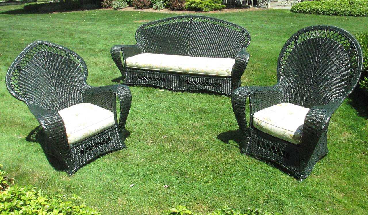Three-Piece Art Deco wicker suite in dark green painted finish. Large scale width and height with one chair having rounded back form & the other a peaked spade shaped back.  High style Art Deco form with a closely woven pattern flaring from the