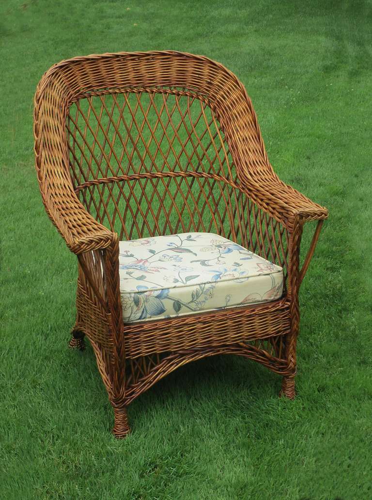 Bar Harbor wicker armchair in natural honey-toned stained finish. Classic rounded backrest and wide flat arms with open woven diagonal latticing. Pineapple twist-wrapped feet. Made of willow.
