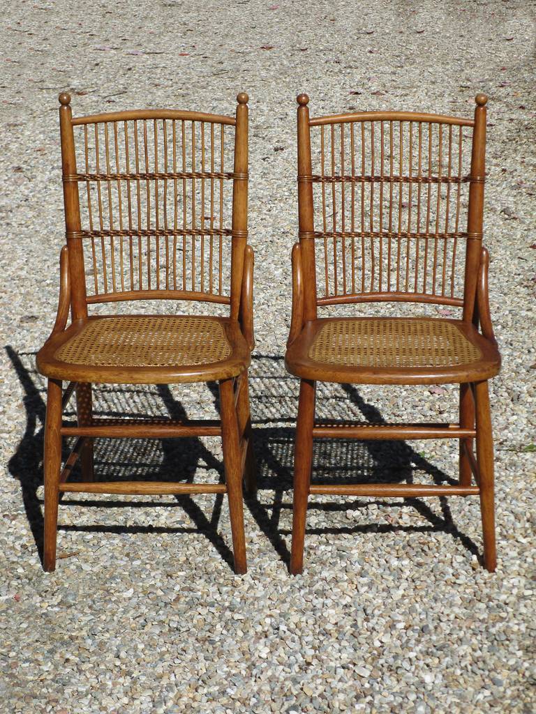Pair of wicker dining chairs in natural stained finish. Oak frames, back panels with evenly spaced vertical reeds, pressed cane seats.