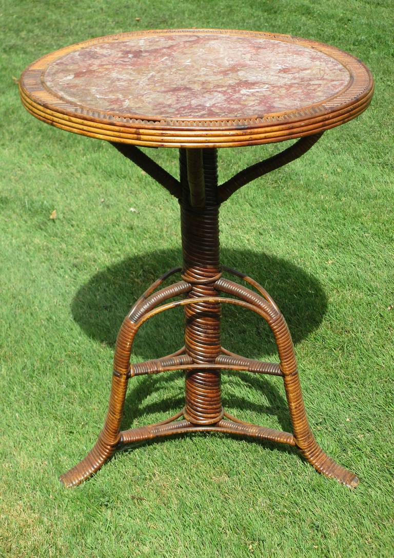 Rare American antique wicker marble top table.  Highly unusual, it is thought to be custom made from the late 1800s.  An elegant piece yet having rustic Adirondack elements.  Round marble surface in hues of deep rose, pink and white veining.  Top