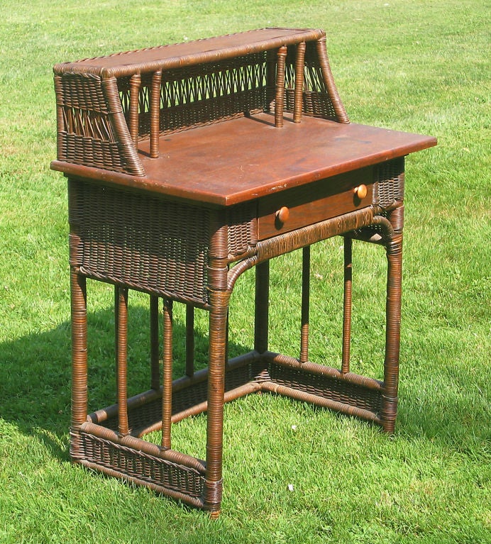 Unusual wicker desk/dressing table in natural stained finish. Solid woven panels and decorative cane-wrapped dowels, large gallery with solid weave surrounding open lattice center panel. Surfaces & single drawer of solid oak.