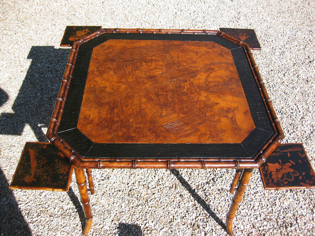 Unusual game table of faux bamboo with gesso pictoral of a Japanese Geisha house.  Black paint with appealing alligatoring borders the scene.  A moongate, mythical animals and intriguing symbolism is interspersed among more than a dozen awaiting
