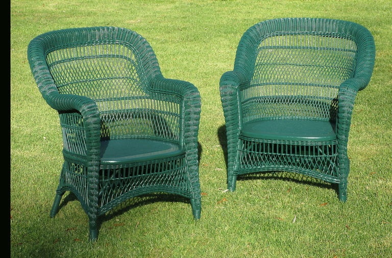 Pair Victorian wicker armchairs in green painted finish. Classic rounded back form with serpentine roll from crest to arms continuing in taper to feet. Gently arched skirts.


