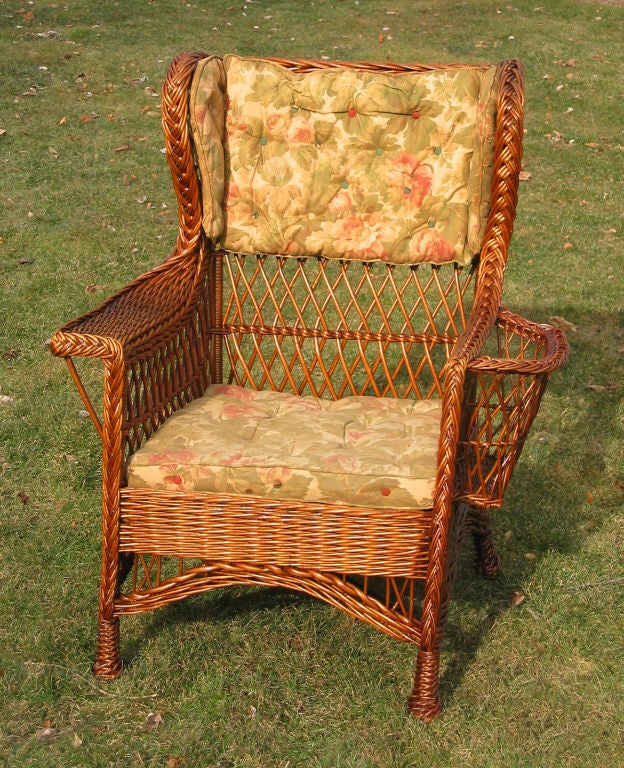 Large scale Bar Harbor wicker wingback armchair in natural stained finish. Deep seated with high level back. Large magazine pocket woven into left arm, wide flat right arm. Four decorative twist-wrapped feet, woven seat. Last photo shown with