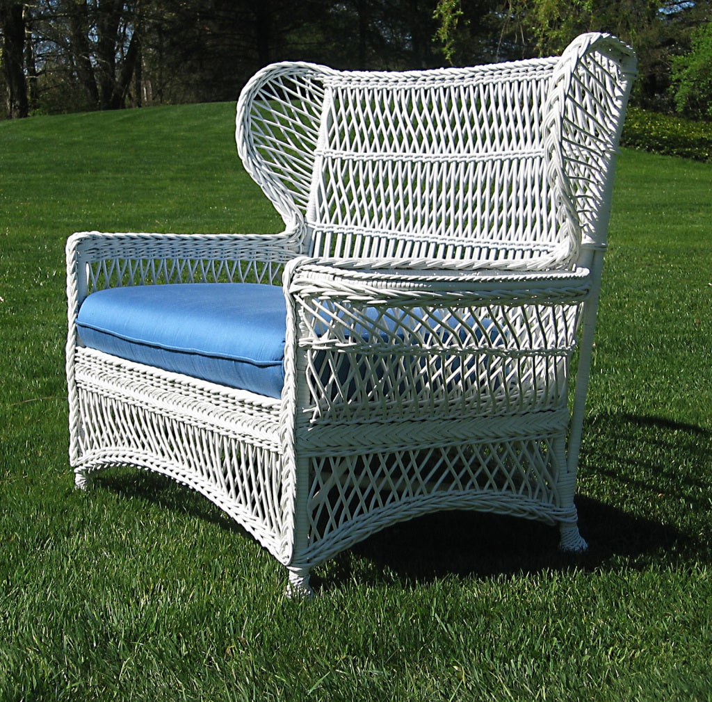 Unusual Bar Harbor wingback settee with magazine pocket woven into left arm & solid woven wide flat right arm.  Closely woven latticework overall.  Arched skirting & four twist-wrapped feet.