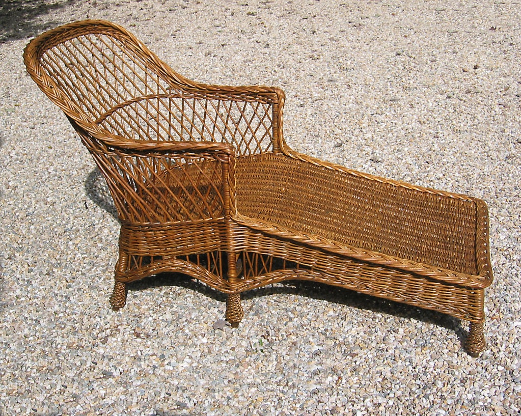 Bar Harbor wicker chaise longue in honey-toned natural stained finish. Braided arms, six pineapple-twist feet. Seating area angled lower at footrest. Woven seat platform for cushion.