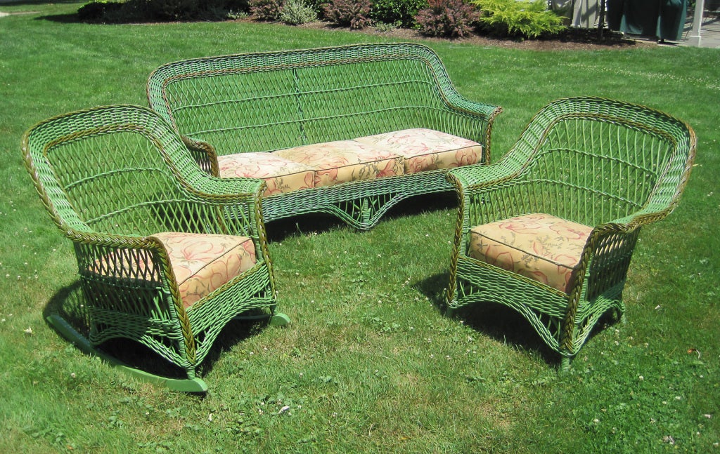 Three-piece Bar Harbor wicker set in old green painted finish with bronze colored trim. (can be re-painted any color on request). Matching sofa, armchair and rocker in traditional form with hallmark latticed reeds, wide arms, braided border and