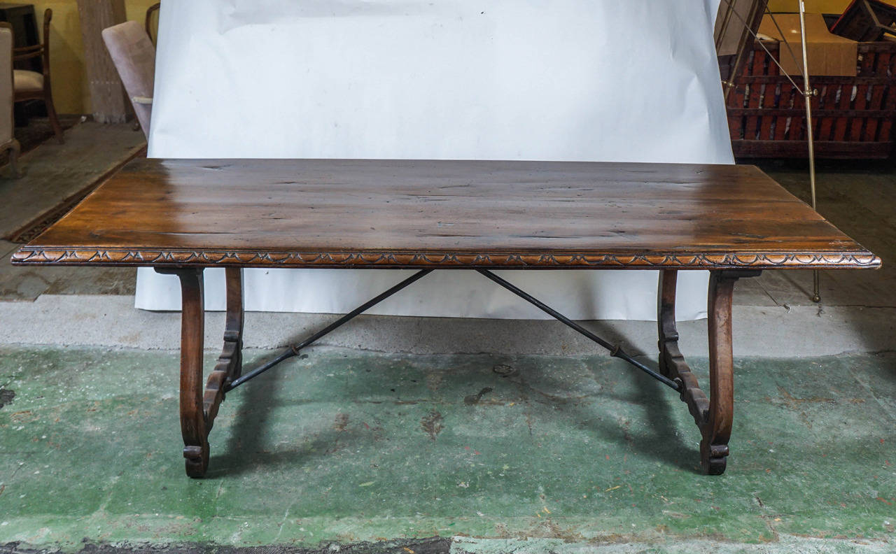 One of the great features of this dining table is the years of waxed patina on the surface. Hand-carved walnut with repeat design decorates the edges. Iron braces secure the Baroque legs.