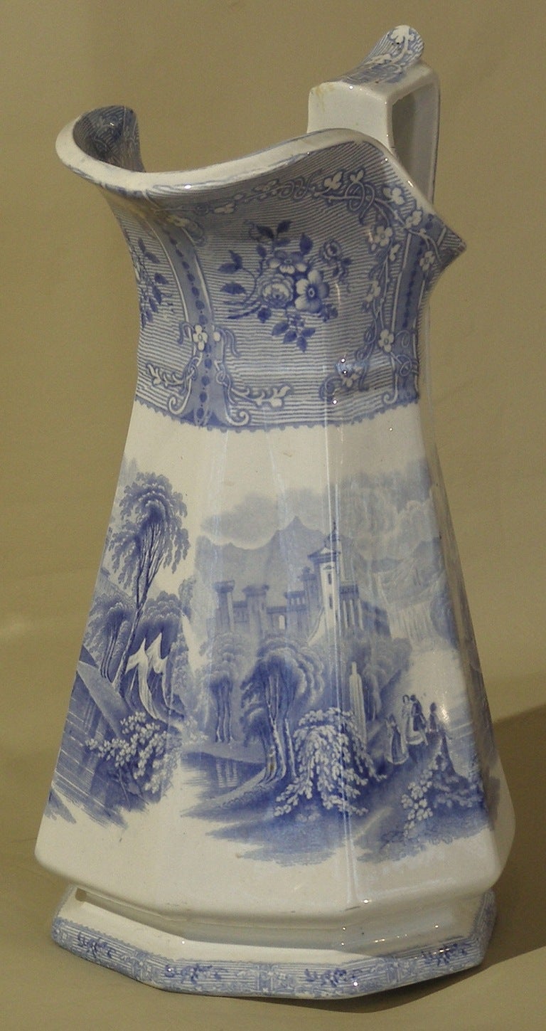 This pottery transfer ware pitcher in light blue on white has a scenic 
view titled on the bottom 