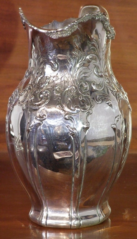 A very fine and heavy engraved and repousse' ornamented sterling pitcher. It is American and while it has all sorts of writing on the bottom it does not have a maker's mark. The marks on the base are 