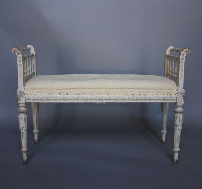 Swedish window bench in the Gustavian style, circa 1900, with upholstered seat and lotus carving on the round legs. The armrests have turned spindles and bellflower carving on the rails.