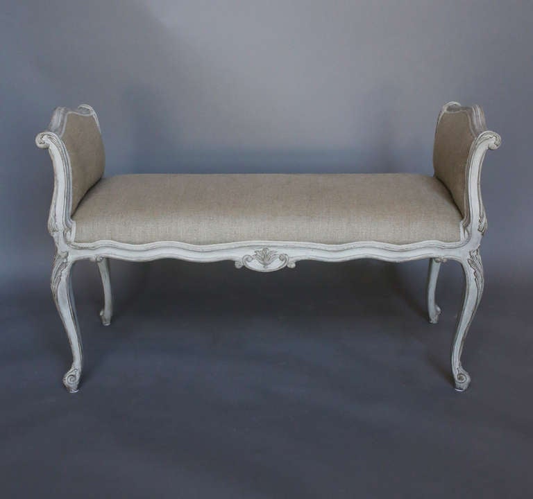 Freestanding Swedish bench, circa 1880, in the rococo style having cabriole legs with foliate carving at the knees and whorl feet. The carving continues up the outwardly curving armrests and appears again as center devices on the seat rails. An
