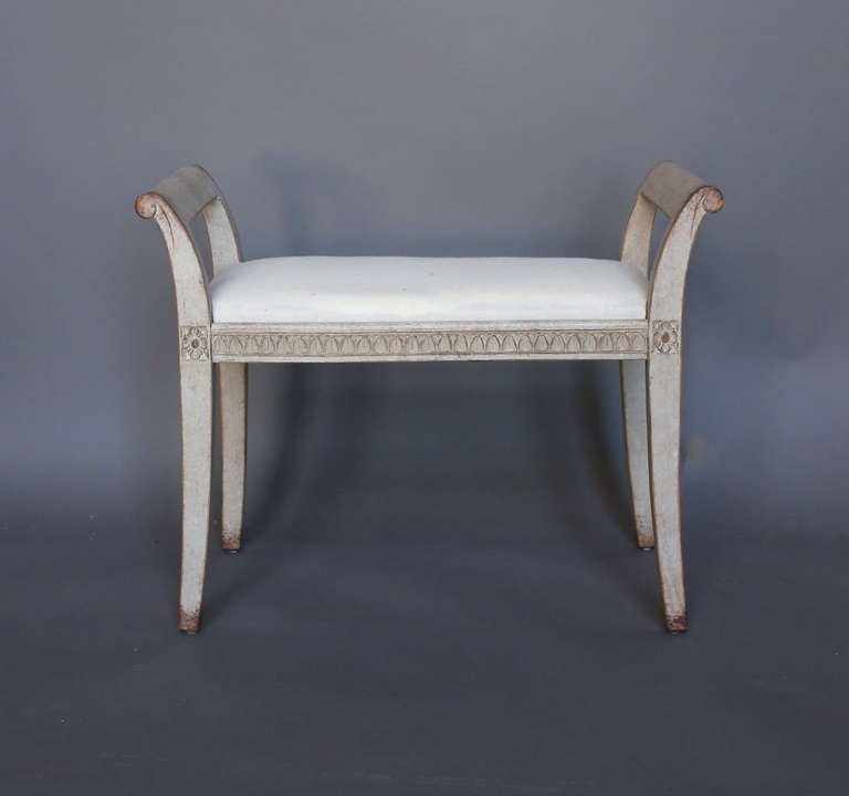 Swedish bench in the Gustavian style, circa 1900, with upholstered seat and saber legs terminating in nicely curved armrests. Lambs tongue molding around the sides.
