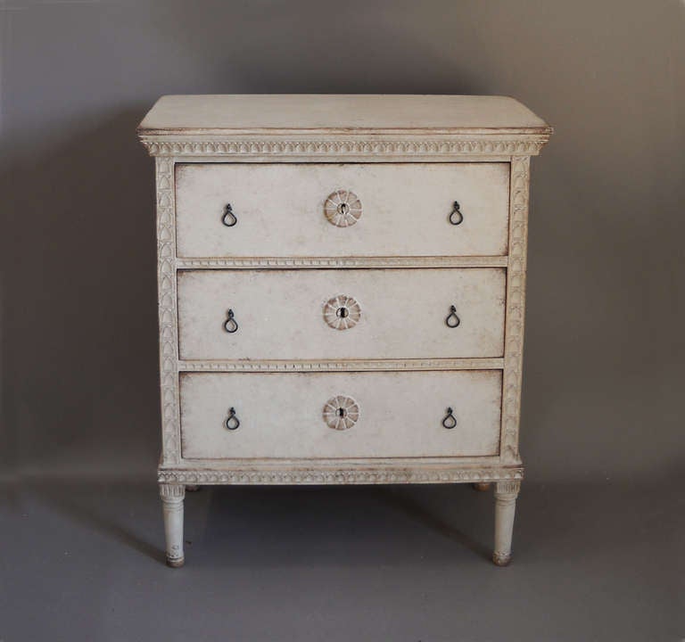 Chest of three drawers, Sweden circa 1900, with a central medallion on each drawer and lambs tongue carving around the frame. Hand wrought iron pulls.