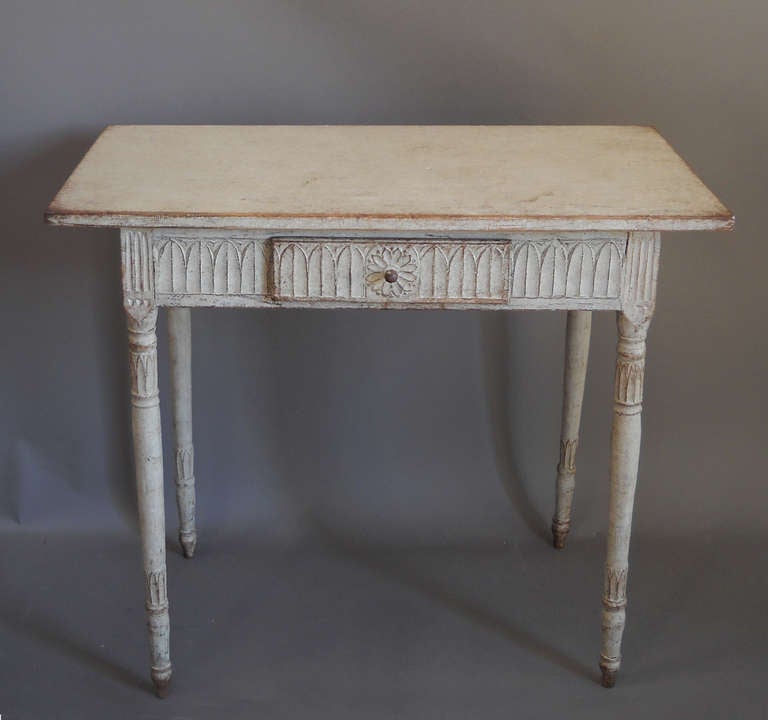 Late Gustavian or neoclassical side table, Sweden circa 1810, showing Egyptian influence in the lotus carving around the apron and on the legs. The single drawer has a wooden pull.