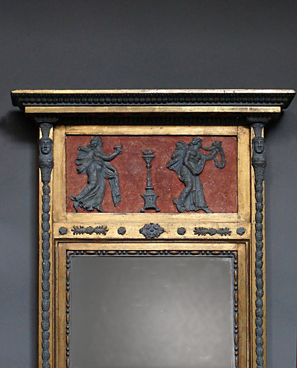 Period neoclassical mirror, Sweden, circa 1820, with original two-part mirror glass and back. The top frieze features two female figures in bas-relief bearing symbols of victory. Below the mirror is a panel with sphinxes. The entire frame is