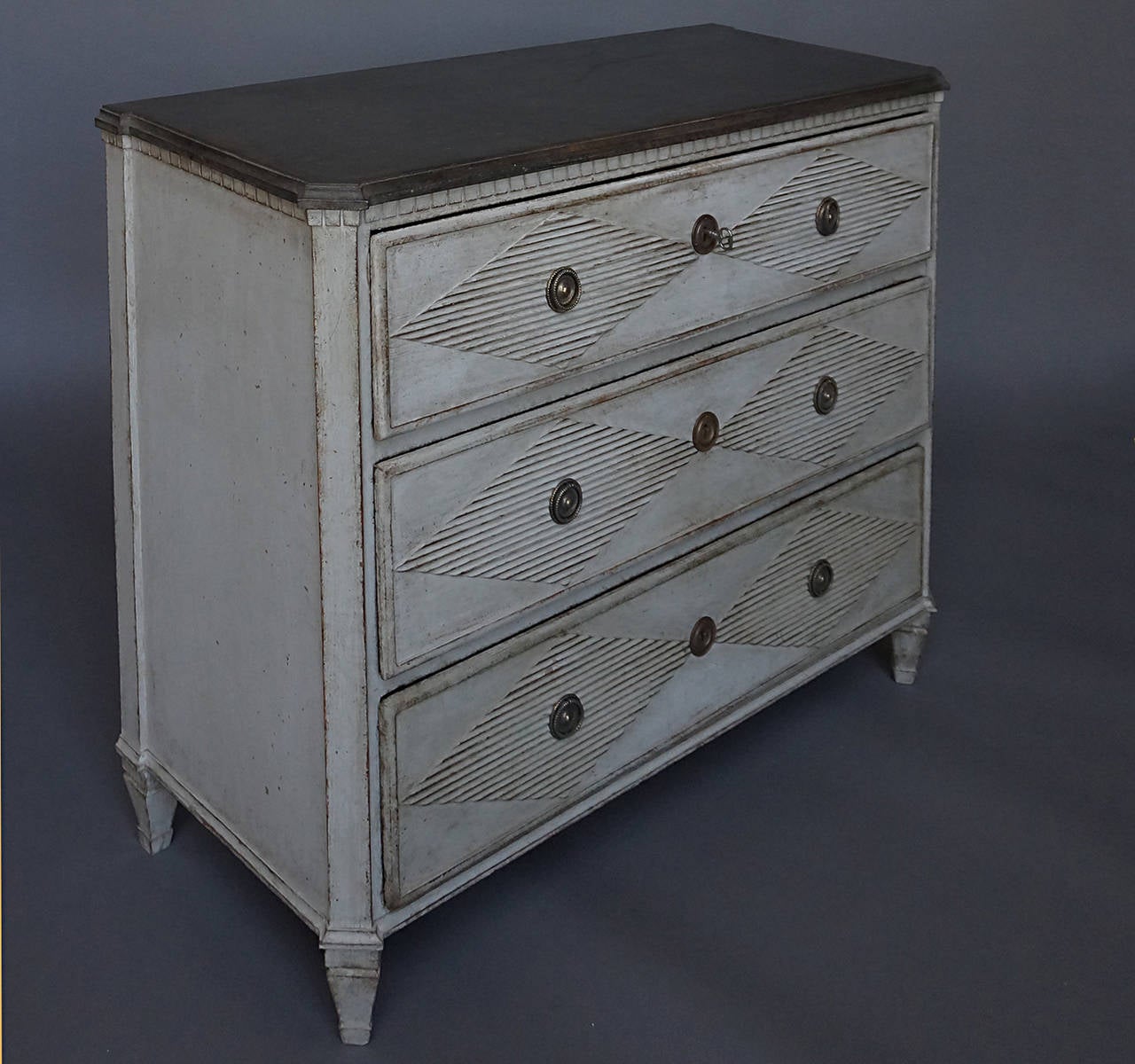 Mid-19th century Swedish chest of drawers, circa 1840, with dentil molding around the black painted top, canted corners and two reeded lozenges on each drawer front. Tapering square legs.